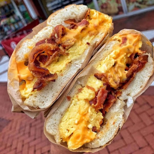 Two Plainview Bagel Cafe breakfast sandwiches with scrambled eggs, melted cheese, and crispy bacon.
