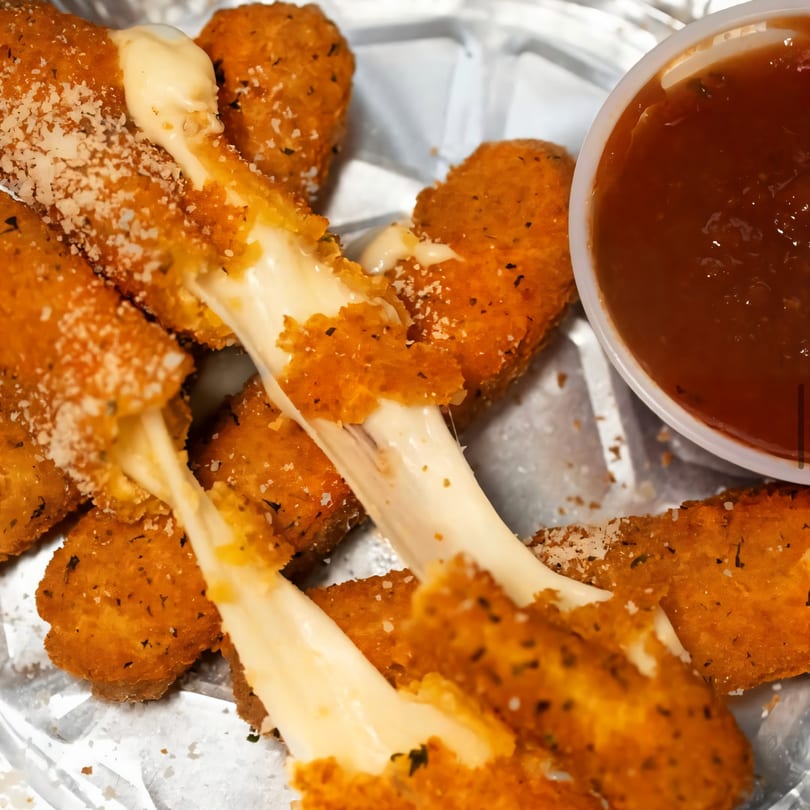 Golden-brown mozzarella sticks with melted cheese stretching, served with a side of marinara sauce.