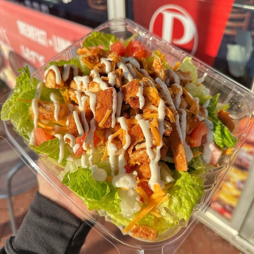 A Plainview Bagel Cafe salad with crispy chicken, cheese, tomatoes, and ranch dressing.